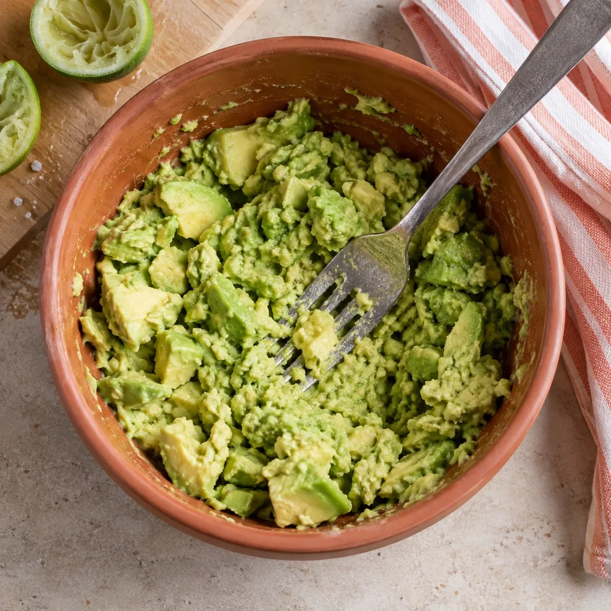 Avocado wordt met een vork grof geprakt in een kom