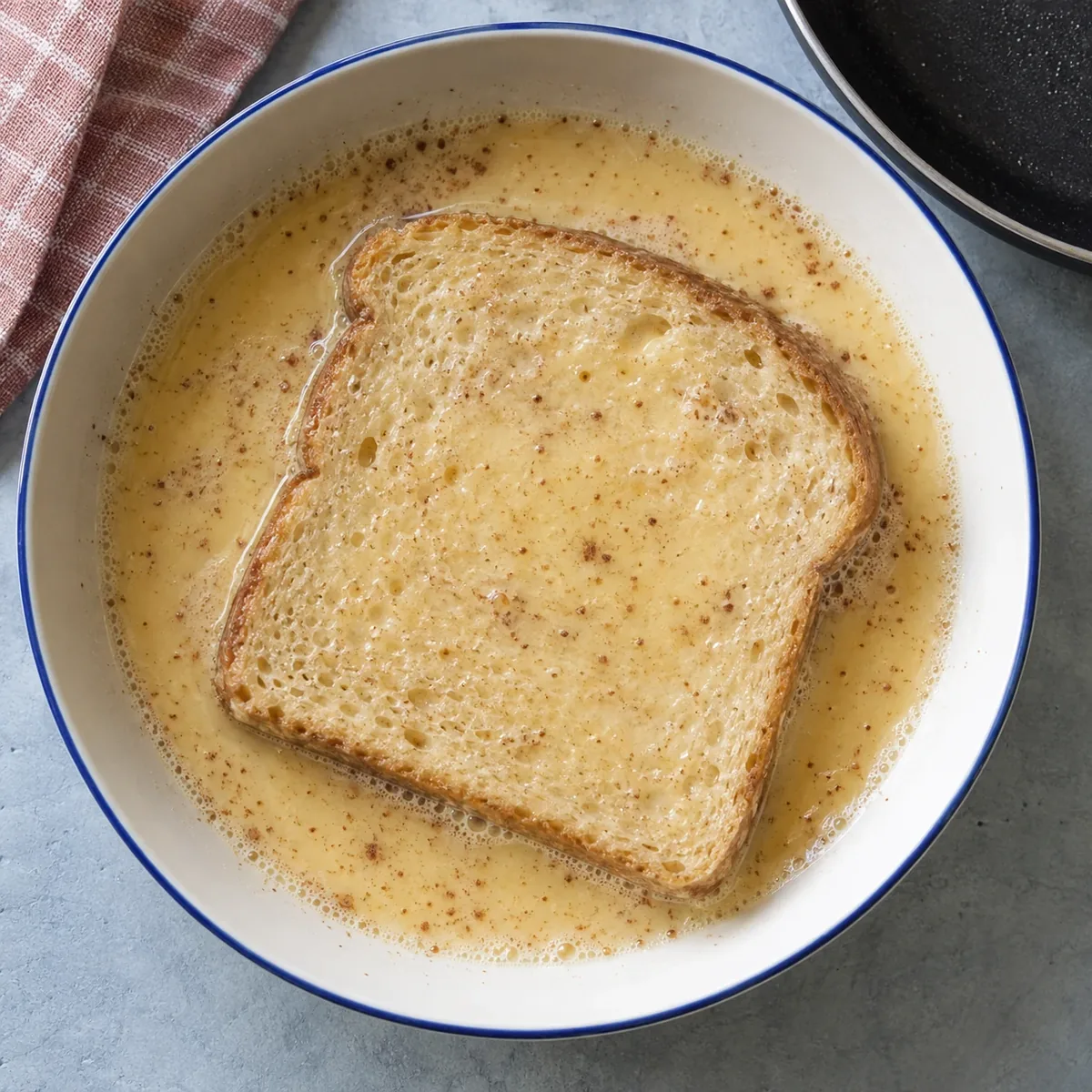 Een sneetje brood dat in het eiermengsel ligt